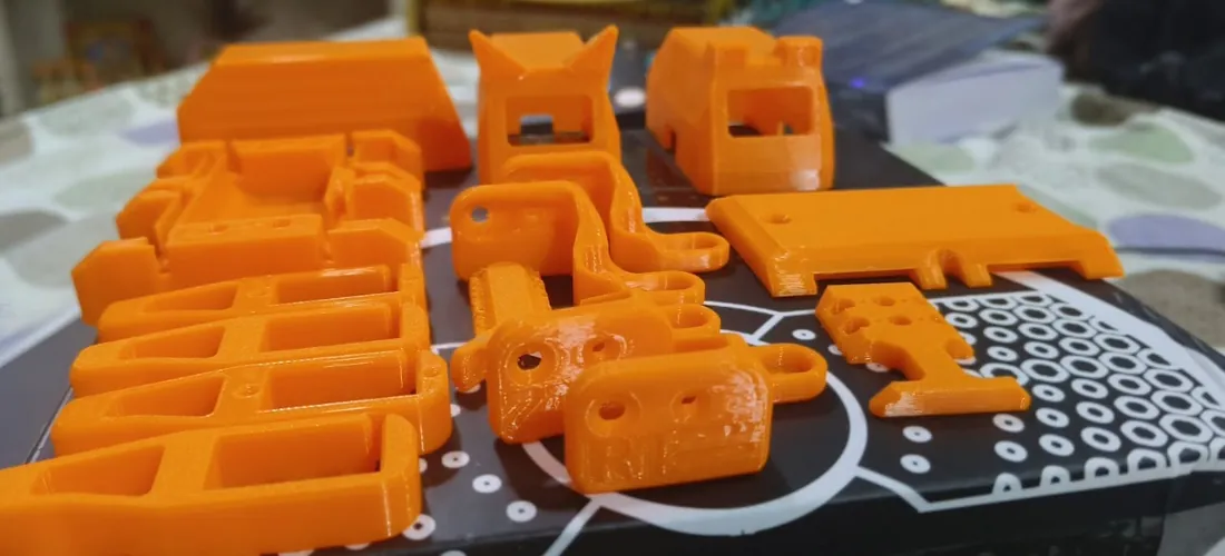 Orange 3D printed parts still on the printer bed